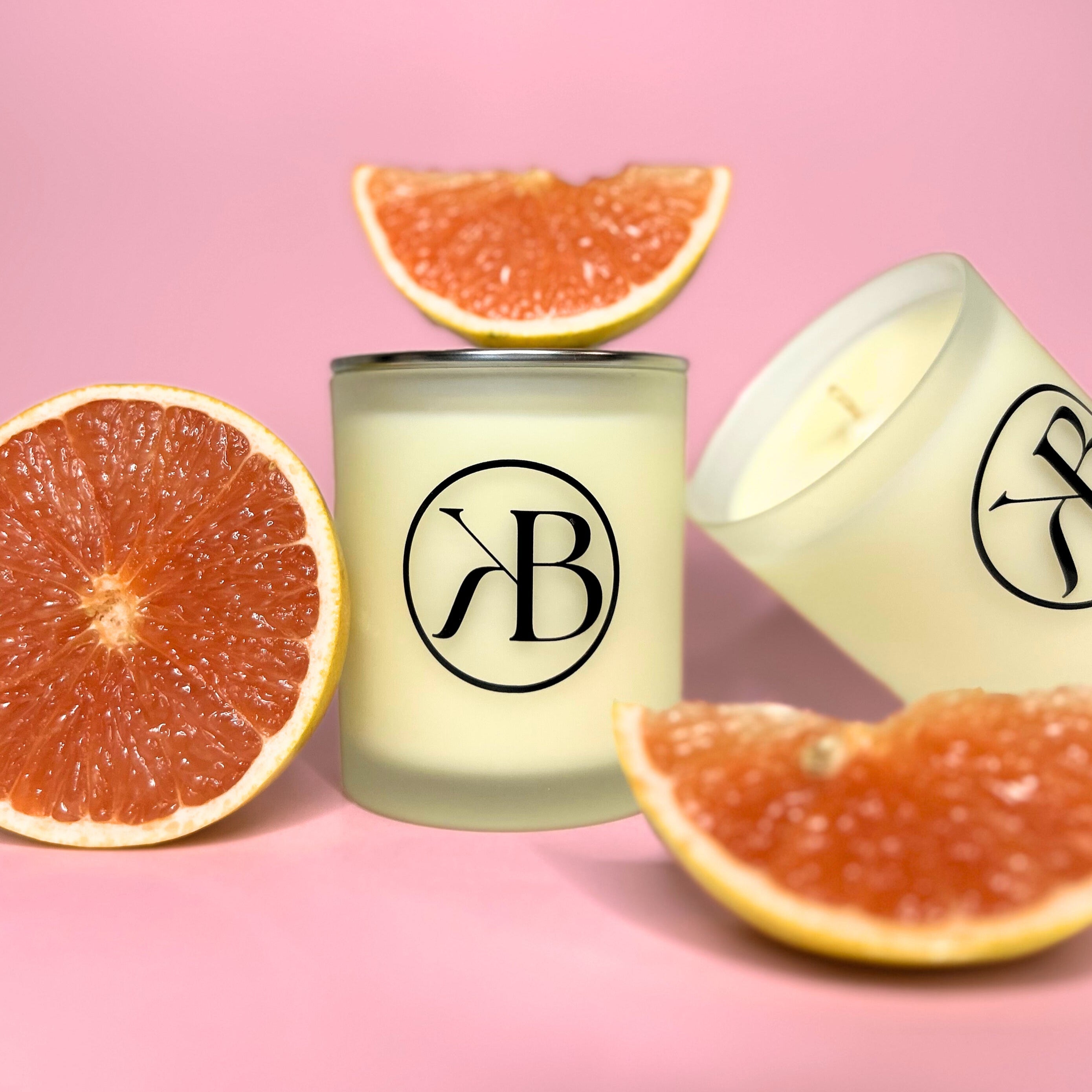Premium handmade candle featuring natural citrus aromas, styled with grapefruit decoration and frosted glass jars.